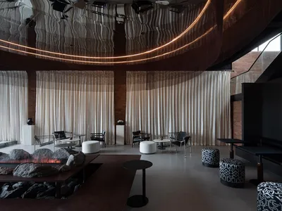 Comfortable modern dining space with a large table, couches, and a fireplace, surrounded by warm lighting