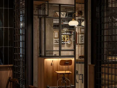 Dimly lit casual dining area with a dining table and chairs, surrounded by tile walls and additional tables in the background