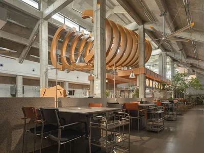 A well-lit restaurant interior with modern design, multiple dining tables, and comfortable seating options