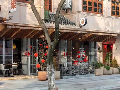 A modern Asian restaurant with a dining area, potted plants, and red lanterns outside, creating a comfortable and inviting atmosphere