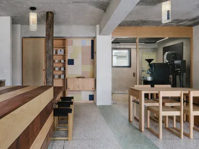 Modern kitchen with wooden floors and walls, featuring a dining table and chairs, with cups on surfaces, conveying a clean and organized atmosphere with a focus on functionality and aesthetics