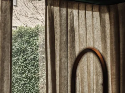 Bathroom with a metal sink under a window, surrounded by curtains, with natural light entering through the window