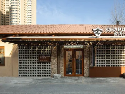 A modern Asian restaurant with a brown wooden exterior, featuring a large doorway and comfortable seating areas inside