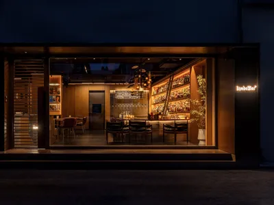 溫馨酒吧餐廳配木質家具、椅子與餐桌，柔和燈光照亮，飾以酒瓶與玻璃杯