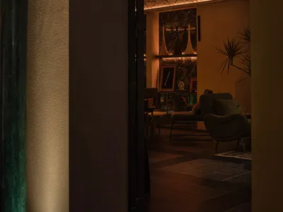 Cozy living space with an archway, two chairs, a potted plant, and a sense of depth and connection to another room