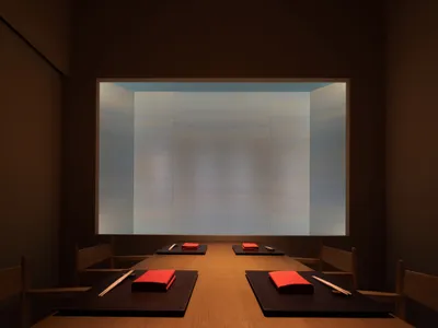 Cozy dining space with a long wooden table, red napkins, and dim lighting