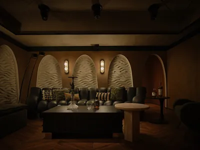 Cozy living space with a large couch, chairs, a dining table, and decorative vases, set in a room with arches and a warm atmosphere