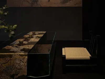 深色調餐廳空間，配有玻璃餐桌、椅子與各式物品，周圍環繞較大的客廳區域，內有沙發