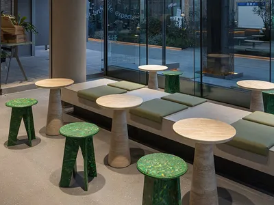 Bright restaurant interior with natural light, multiple dining tables, and green cushions