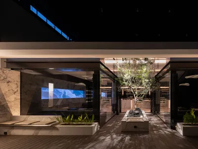 A warm and inviting indoor space with a large tree in the center, surrounded by chairs and seating options