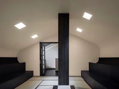 Dimly lit living space with two couches and a wooden pillar, creating a cozy atmosphere