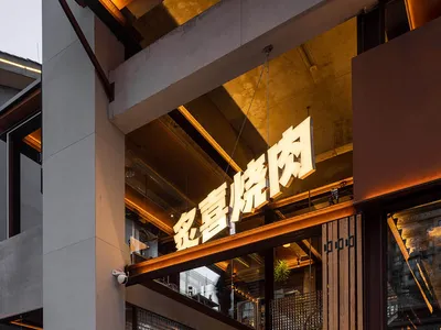 A modern Asian restaurant with a wooden staircase, potted plants, and a warm inviting ambiance