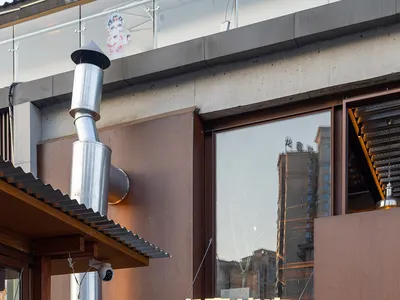 Exterior view of an Asian restaurant with a brown facade, large window, and modern yet warm architecture featuring wood and metal elements