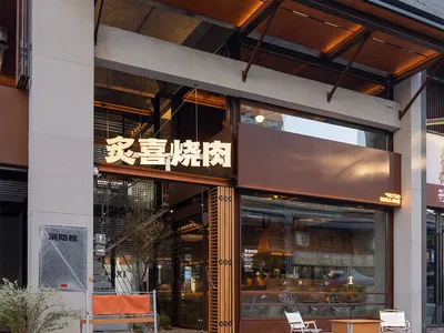 A modern Asian restaurant with wooden paneling, chairs, and dining tables, flooded with natural light through a large window
