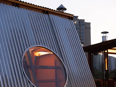 A modern dome-shaped building with a metal exterior, featuring a seating area with chairs and a couch, conveying a sense of innovation and creativity in design