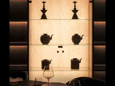 Dining area with a table, wine glasses, bowls, a cup, and decorative vases, set in a sophisticated interior design