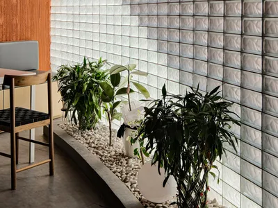 A dining area with a wooden floor, a table, chairs, and potted plants in a restaurant setting