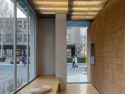 Bright and inviting hotel lobby with a yellow bench, guests walking by, and a welcoming atmosphere