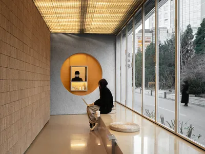 舒適家用辦公空間帶用餐區，自然光線充足，窗邊長椅擺放筆電與兩杯飲品