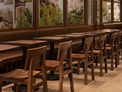 Warm and inviting restaurant interior with wooden tables and chairs, potted plants, and ample seating for guests