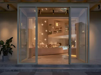 A clean and elegant jewelry store with white walls, vibrant jewelry on display, and potted plants, inviting customers to explore its fine offerings
