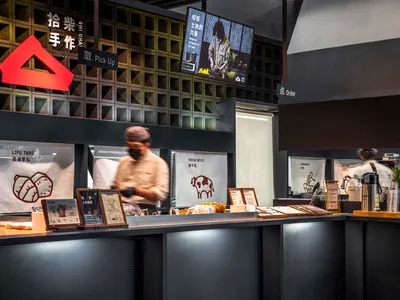 Casual Asian restaurant with a counter displaying food items, a TV on the wall, and two people in the scene