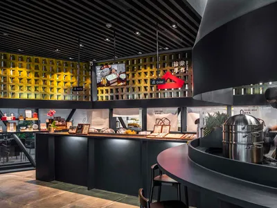 Modern restaurant interior with a black countertop, yellow accents, and seating for customers