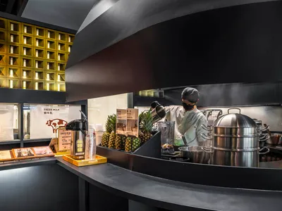 一位男子在黑色檯面前準備食物，周圍環繞各種廚具，營造休閒氛圍的廚房場景