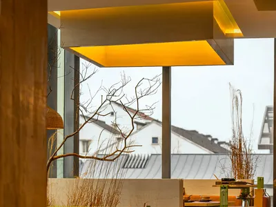 A modern restaurant interior with wooden tables and chairs, featuring a warm and inviting atmosphere with several dining tables and benches