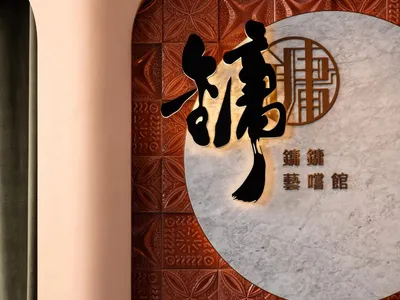 A well-lit Asian restaurant interior with a wall featuring Chinese characters and a tile pattern, creating a warm atmosphere