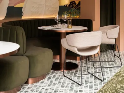 Elegant cafe interior with a dining table, chairs, and swans on the wall, surrounded by pink walls and wine glasses