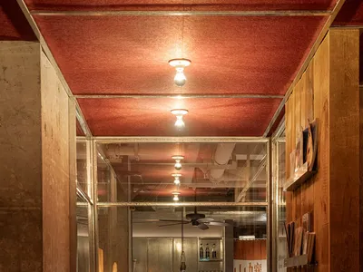 A cozy restaurant dining area with tables, chairs, and bottles, visible through a glass door