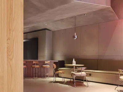 Modern restaurant interior with concrete walls, dining tables, and chairs, creating a stylish and inviting atmosphere