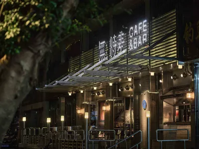 A modern restaurant with a concrete exterior, well-lit and stylish, featuring a prominent sign and inviting atmosphere