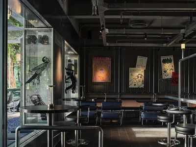 Dimly lit restaurant interior with seating areas, dining tables, and artwork on the walls