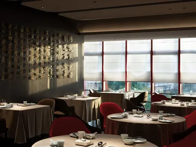 Cozy Asian restaurant interior with dining tables, chairs, and table settings, creating a warm and inviting atmosphere for guests