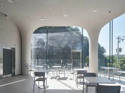 A modern restaurant interior with multiple dining tables and chairs, well-lit for a comfortable atmosphere