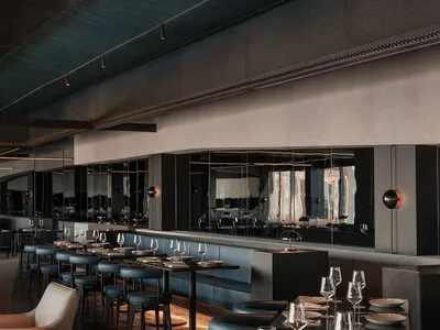 Modern restaurant interior with black and grey tones, multiple tables, chairs, and wine glasses, creating a sophisticated atmosphere