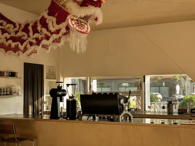 A vibrant Asian restaurant interior with a wooden dragon head, chairs, a dining table, and various cups and bottles, evoking a sense of cultural heritage and tradition