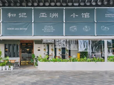 An inviting Asian restaurant with a large sign, potted plants, chairs, and dining tables, creating a pleasant atmosphere for customers