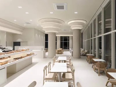 Clean and modern restaurant interior with white walls, beige chairs, and tables, featuring a minimalist dining area with several tables and chairs