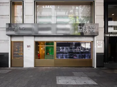 Spacious Asian restaurant with a glass front door, dining tables, chairs, and potted plants, creating a comfortable and inviting atmosphere
