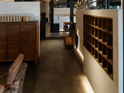 A modern hotel lobby with a large open area featuring dining tables, chairs, potted plants, and vases, creating a welcoming atmosphere