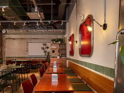 Warm and inviting Asian restaurant interior with wooden tables, red accents, and potted plants
