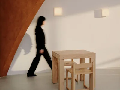 A woman walks past a wooden dining table in a casual restaurant setting with two chairs and wooden walls creating a warm atmosphere