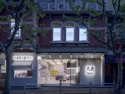 A modern Asian restaurant with white walls, gray floors, and natural light from a large window, featuring chairs and dining tables in a clean and minimalist space