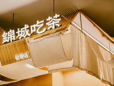 A well-lit Asian restaurant with bamboo walls, fabric hanging items, and a warm atmosphere