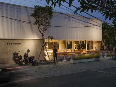 夜晚戶外餐廳場景，設有餐桌、椅子與盆栽，營造溫暖親切的氛圍