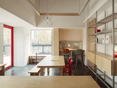 A modern kitchen with wooden floors and walls, featuring a dining table and chairs, and metal accents
