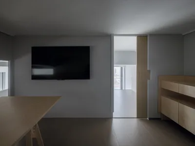 Empty living room with a flat screen TV, wooden floors, and good lighting